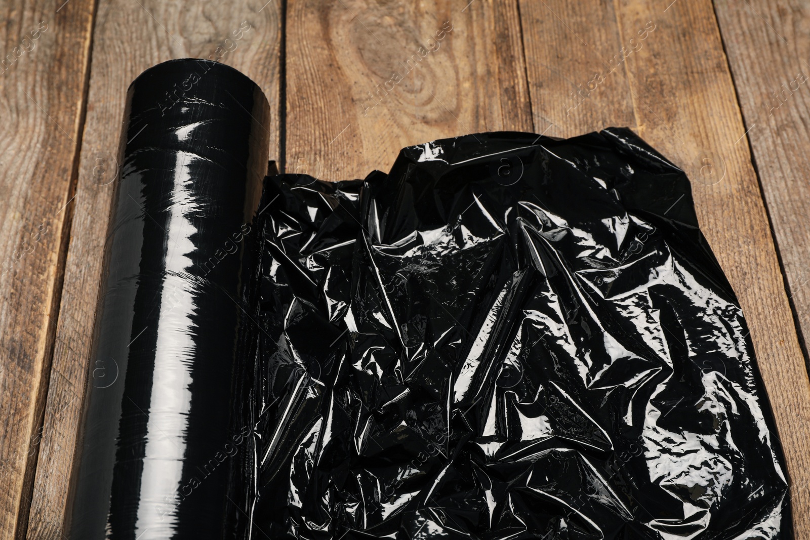 Photo of Roll of plastic stretch wrap film on wooden table, closeup