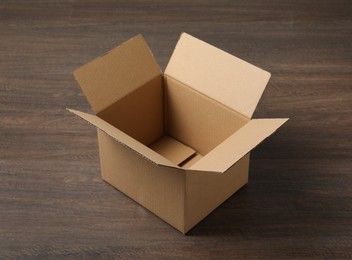 Photo of Empty open cardboard box on wooden table