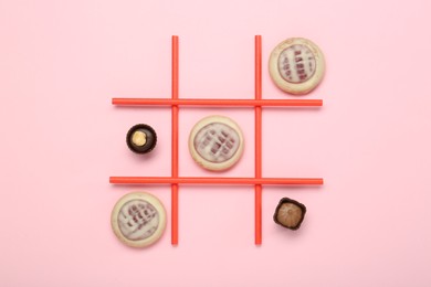 Photo of Tic tac toe game made with cookies and sweets on pink background, top view