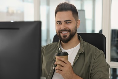 Photo of Happy man with paper cup of coffee in office