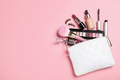 Cosmetic bag and makeup products with accessories on pink background, flat lay. Space for text