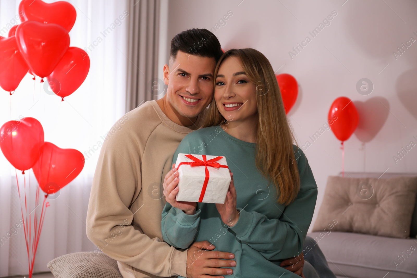 Photo of Lovely couple with gift in room. Valentine's day celebration