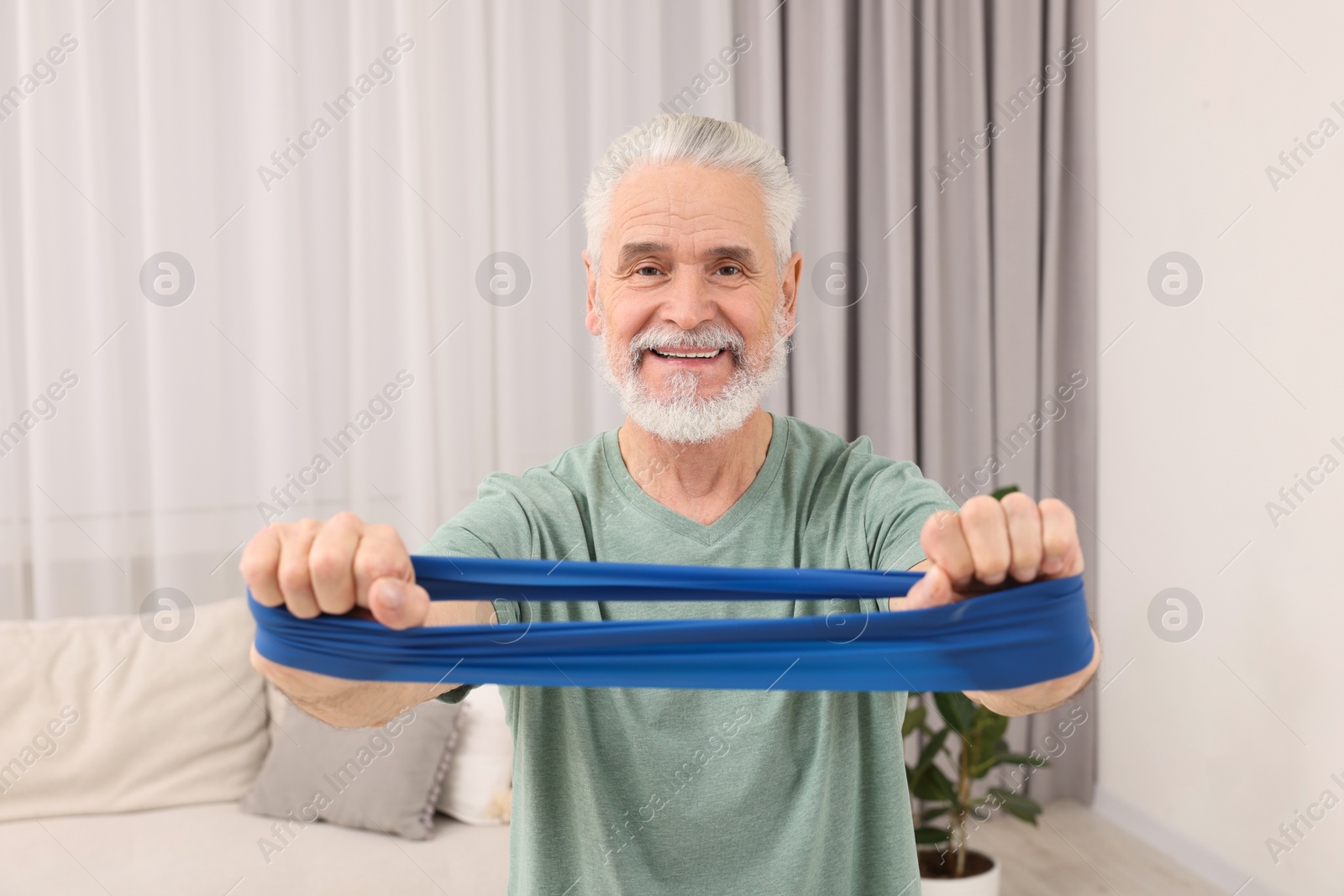 Photo of Senior man doing exercise with fitness elastic band at home