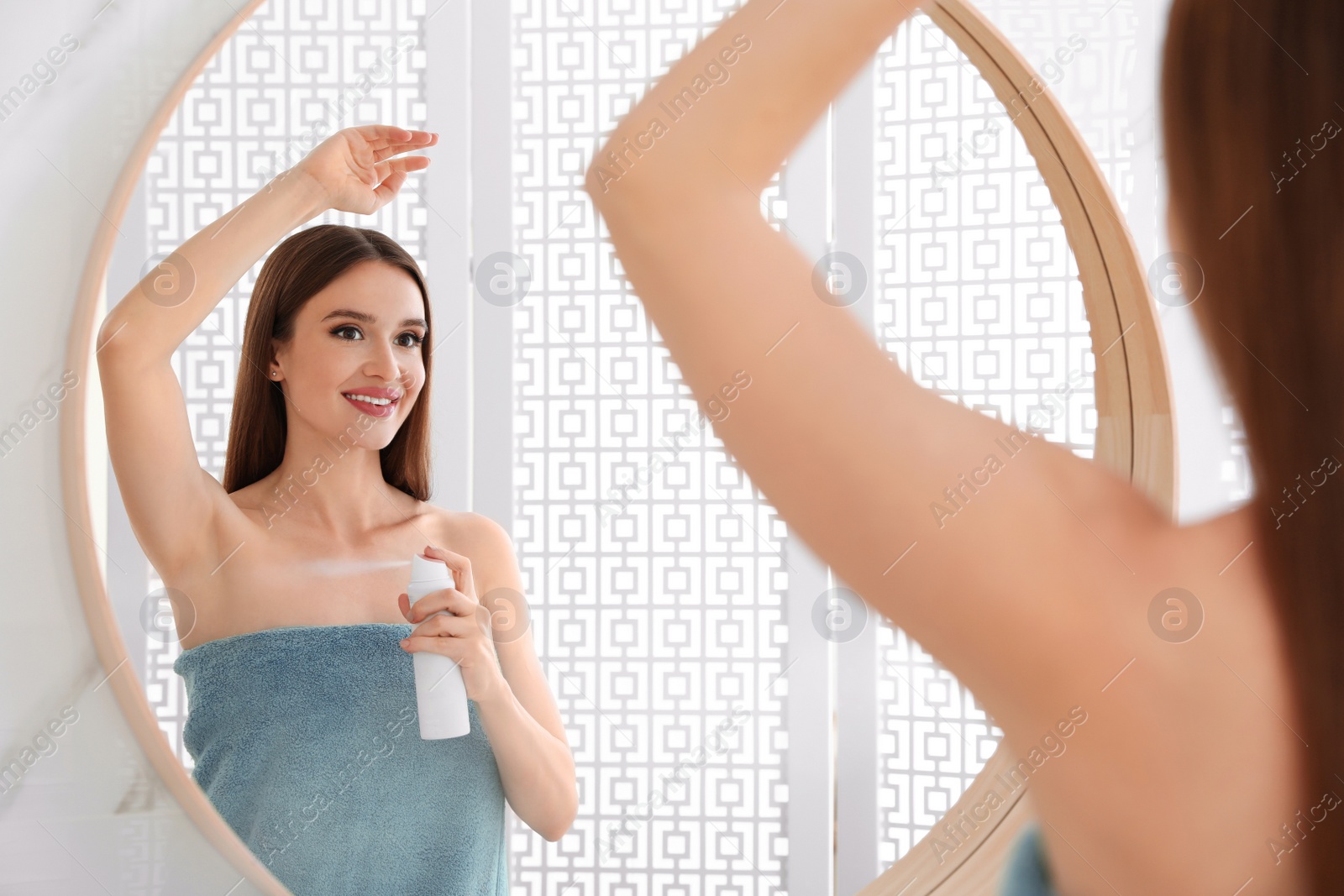 Photo of Beautiful young woman applying deodorant after shower in bathroom