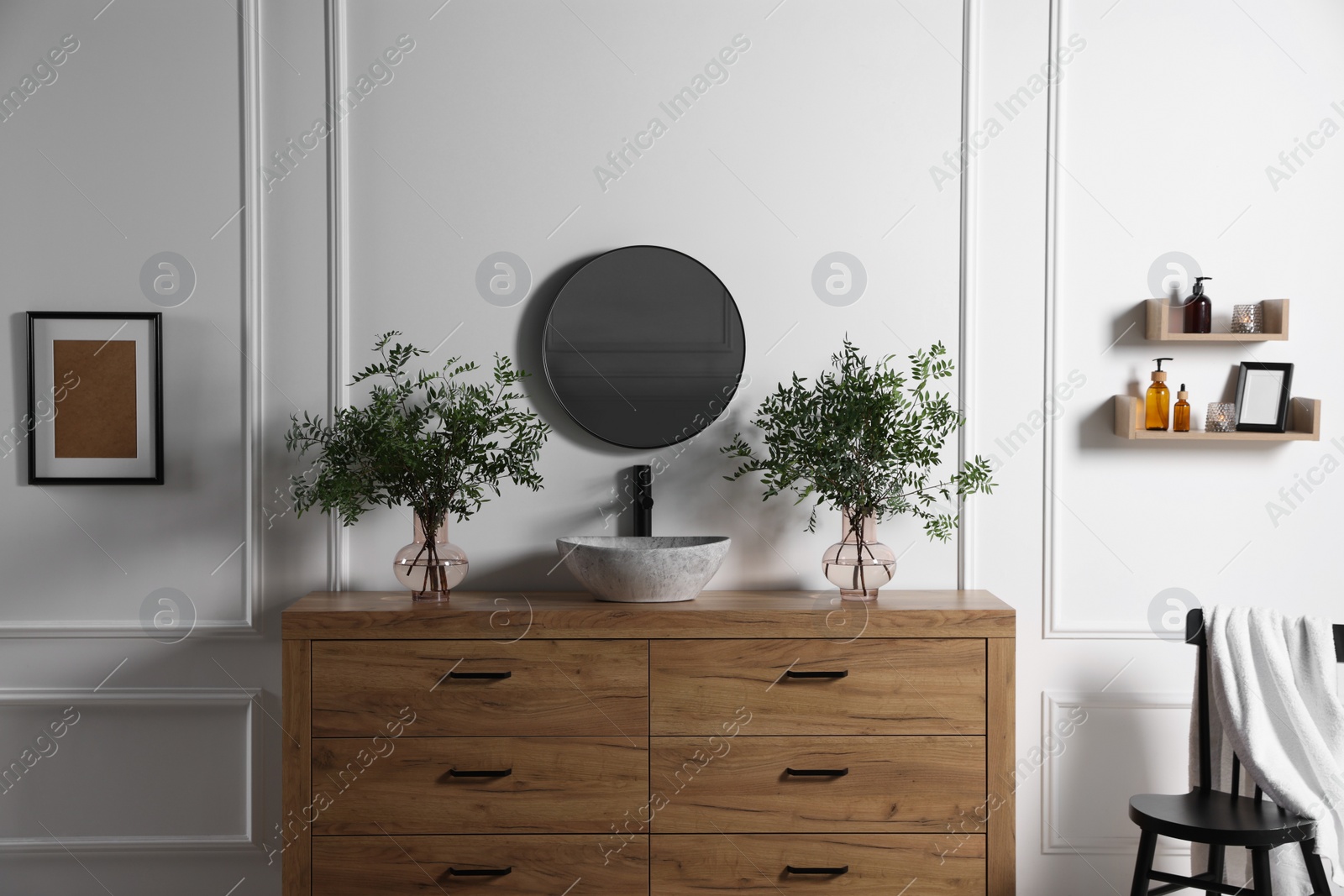 Photo of Eucalyptus branches near vessel sink on bathroom vanity. Interior design