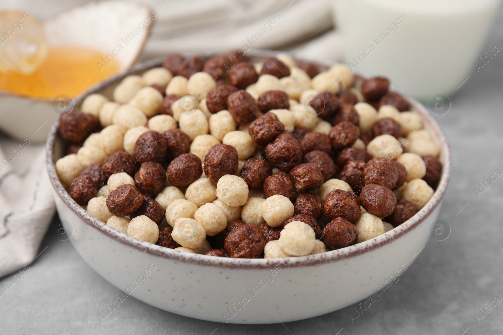 Photo of Tasty cereal balls in bowl on grey table, closeup