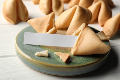 Tasty fortune cookies and paper with prediction on white wooden table, space for text