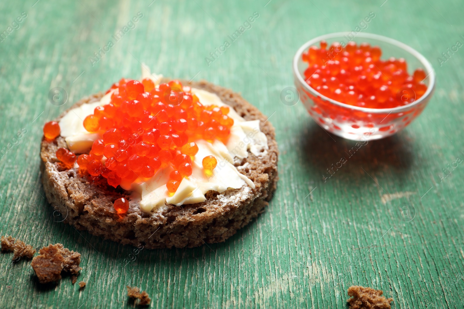 Photo of Delicious sandwich with red caviar on wooden table