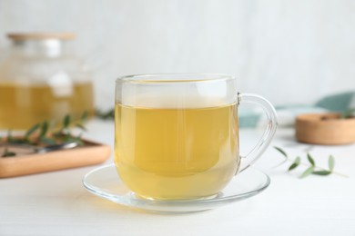 Photo of Glass cup of aromatic eucalyptus tea on white wooden table, closeup