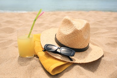 Photo of Straw hat, sunglasses, towel and refreshing drink on sandy beach near sea