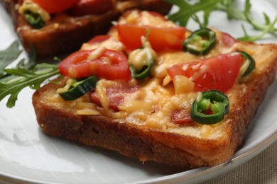 Photo of Tasty pizza toast and fresh arugula on plate, closeup