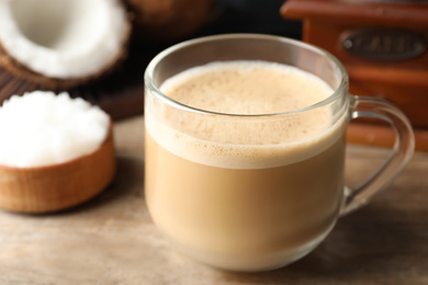 Photo of Delicious coffee with organic coconut oil on wooden table