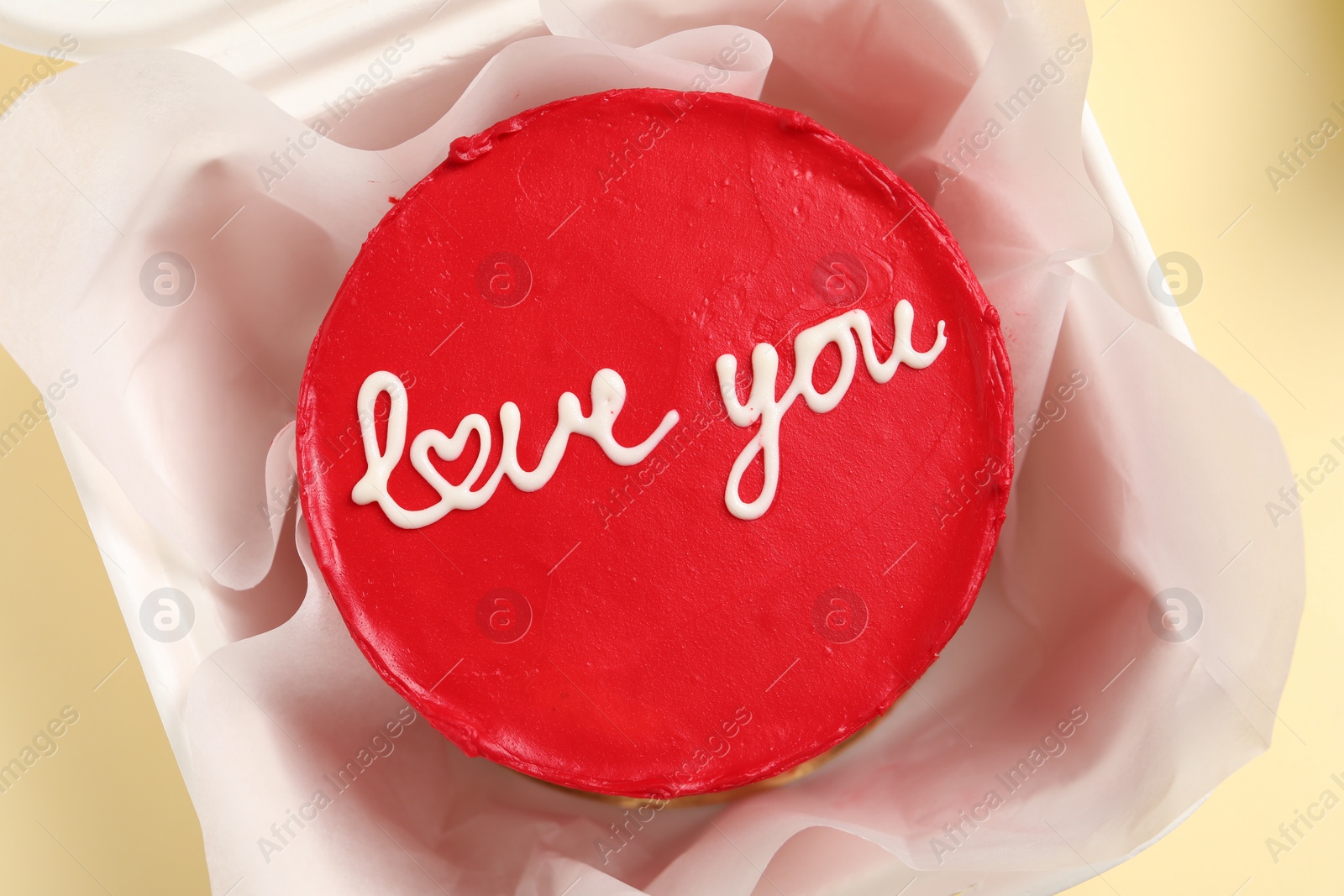 Photo of Bento cake with Love You text in takeaway box on beige table, top view. St. Valentine's day surprise