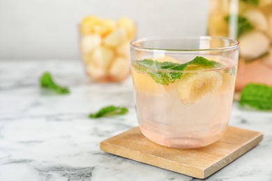 Glass with tasty melon ball drink on table