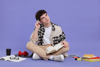 Portrait of student with notebook and stationery sitting on purple background