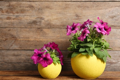 Photo of Beautiful pink petunia flowers in plant pots on wooden table