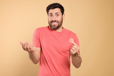 Photo of Man holding condom on beige background. Safe sex
