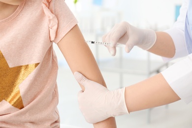 Doctor vaccinating little girl in hospital