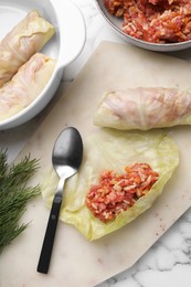 Photo of Preparing stuffed cabbage rolls on white marble table, flat lay