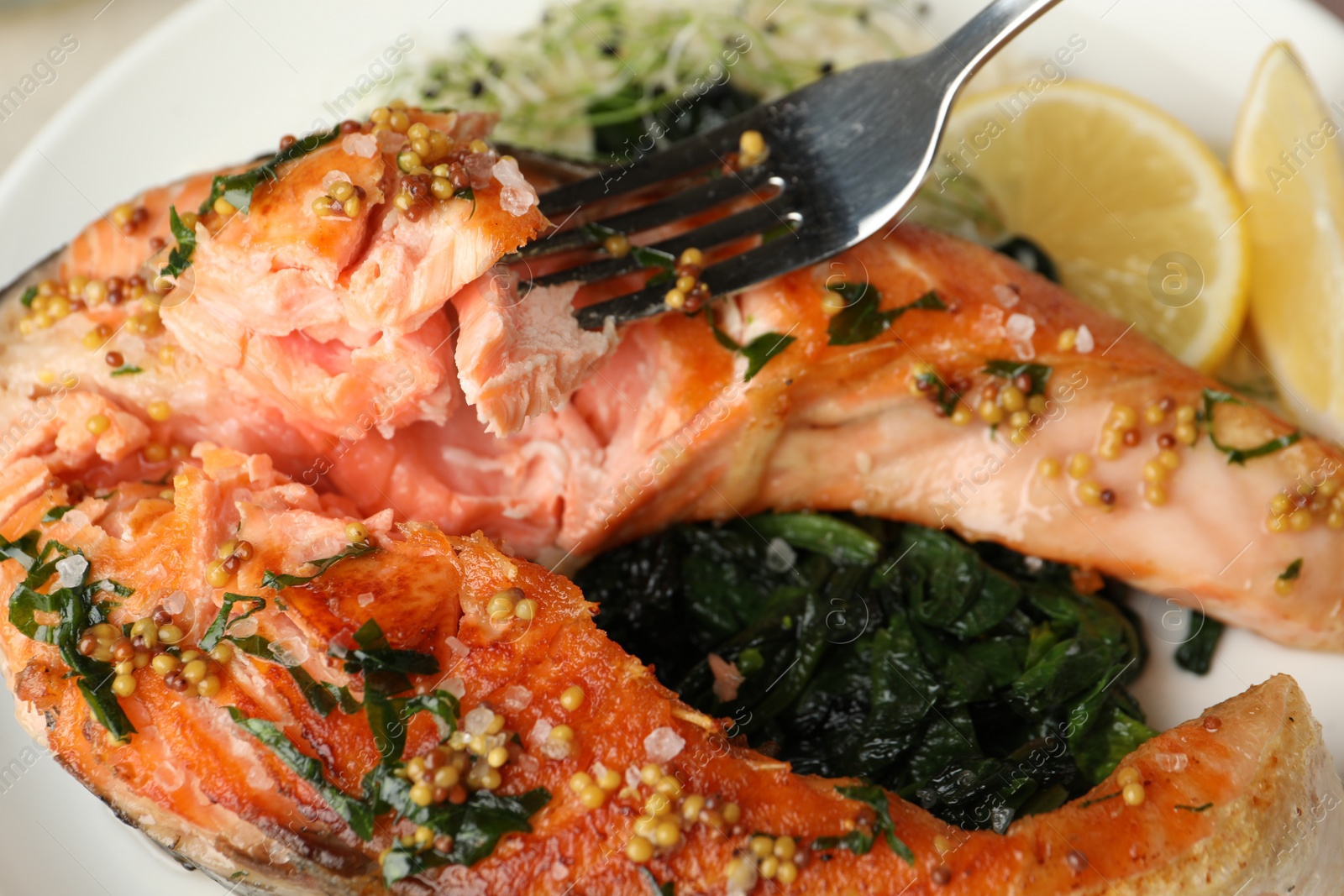 Photo of Tasty salmon with spinach on plate, closeup