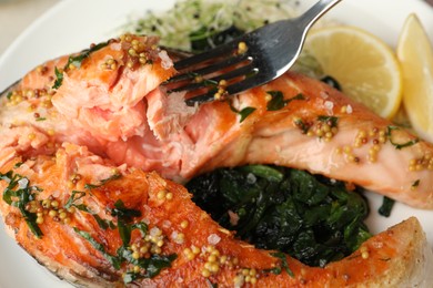 Photo of Tasty salmon with spinach on plate, closeup