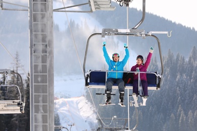 People using chairlift at mountain ski resort. Winter vacation