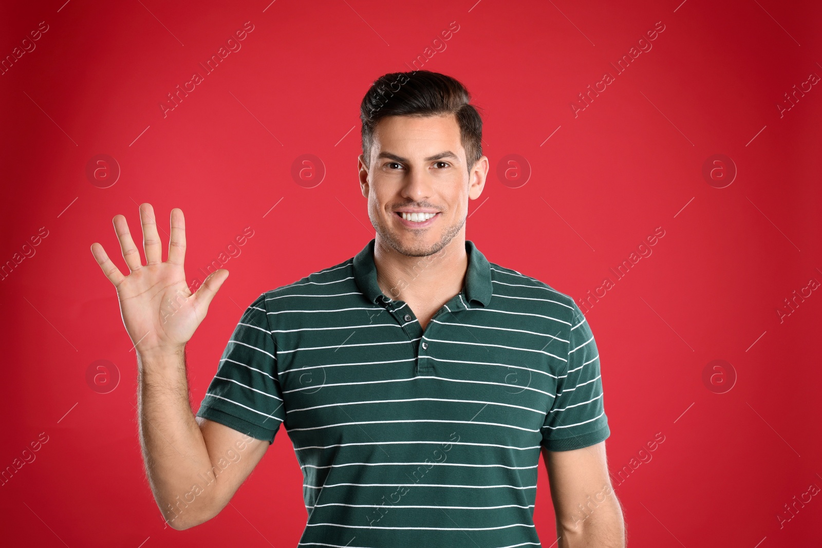 Photo of Man showing number five with his hand on red background