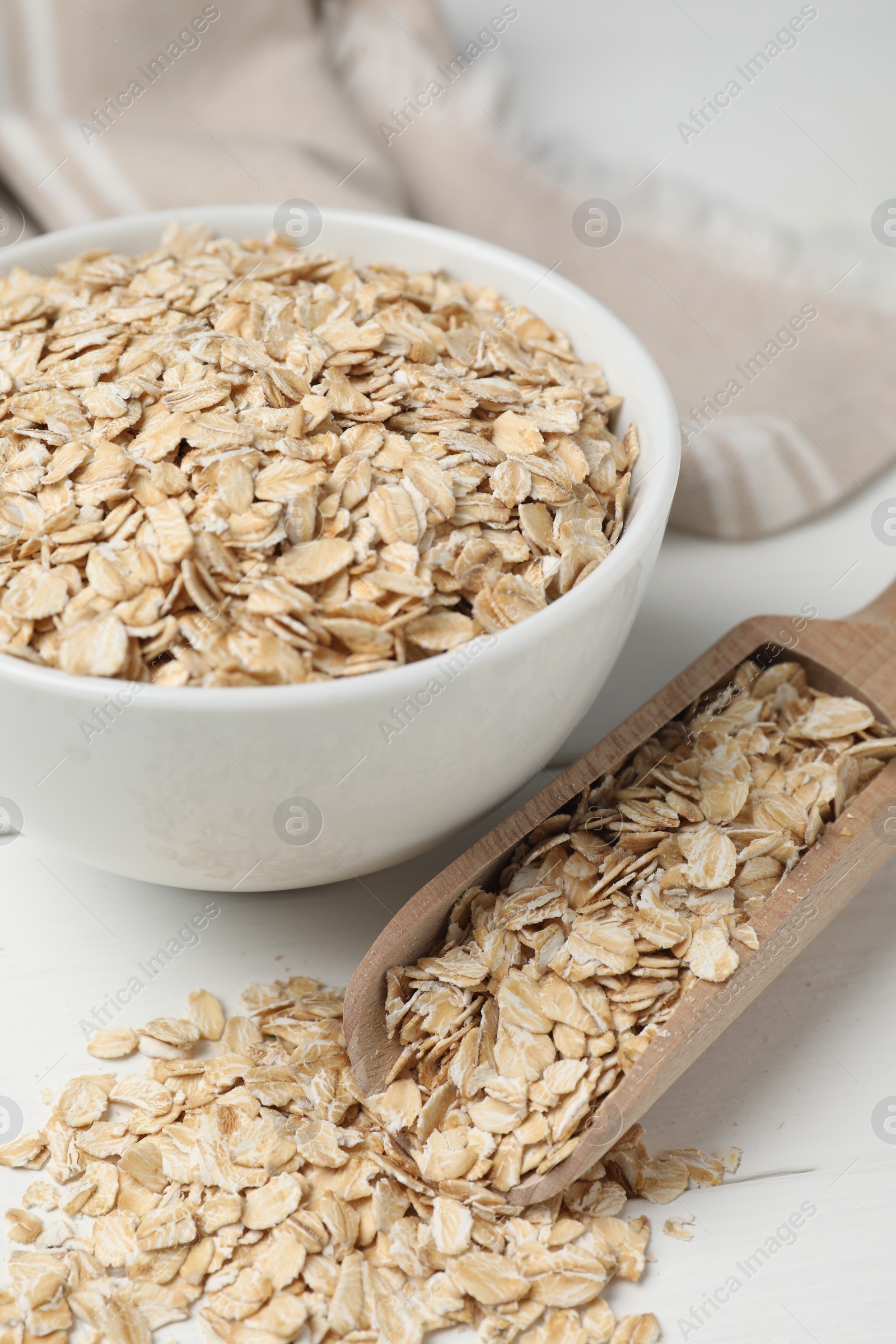 Photo of Bowl and scoop with oatmeal on white wooden table, closeup