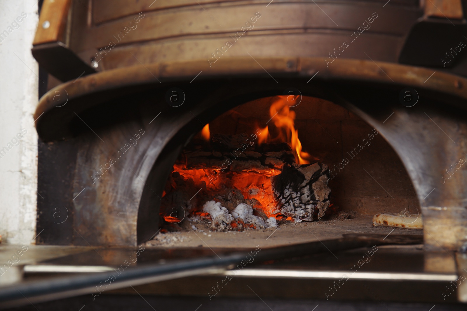 Photo of Oven with burning firewood and tasty pizza in restaurant kitchen