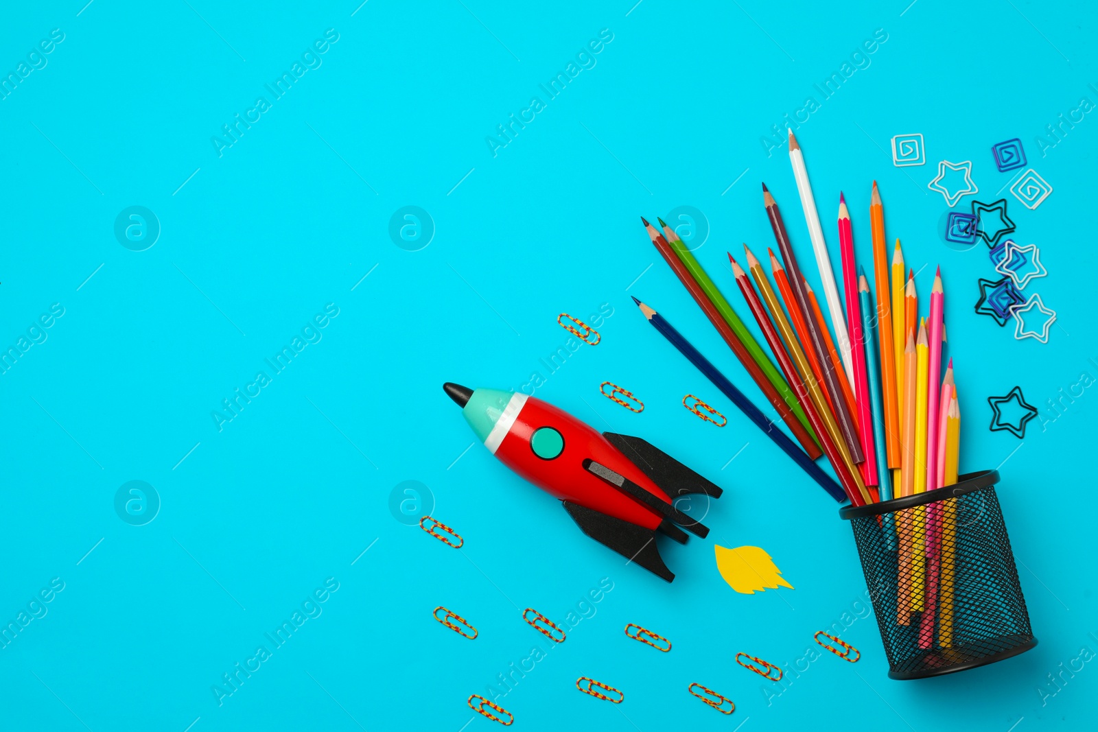 Photo of Bright toy rocket and school supplies on light blue background, flat lay. Space for text