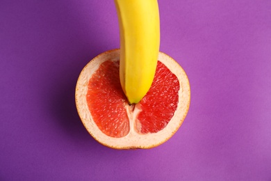 Photo of Fresh grapefruit and banana on purple background, top view. Sex concept