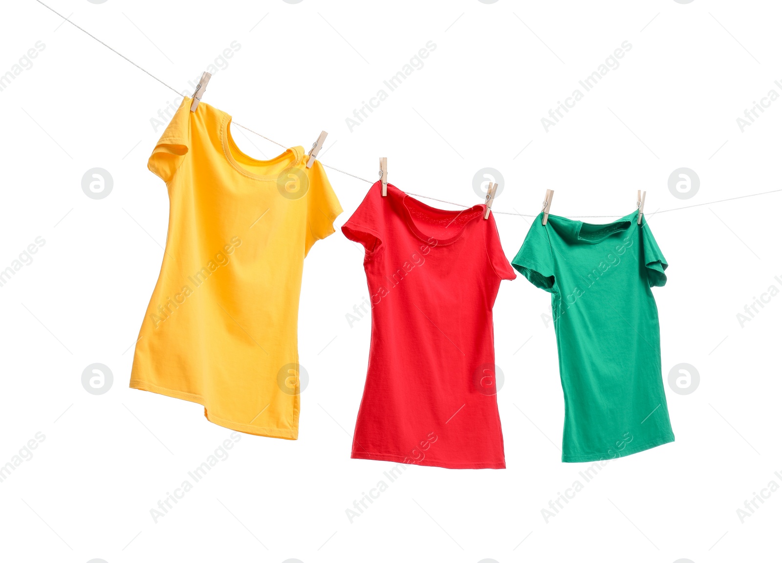 Photo of Different bright t-shirts drying on washing line against white background