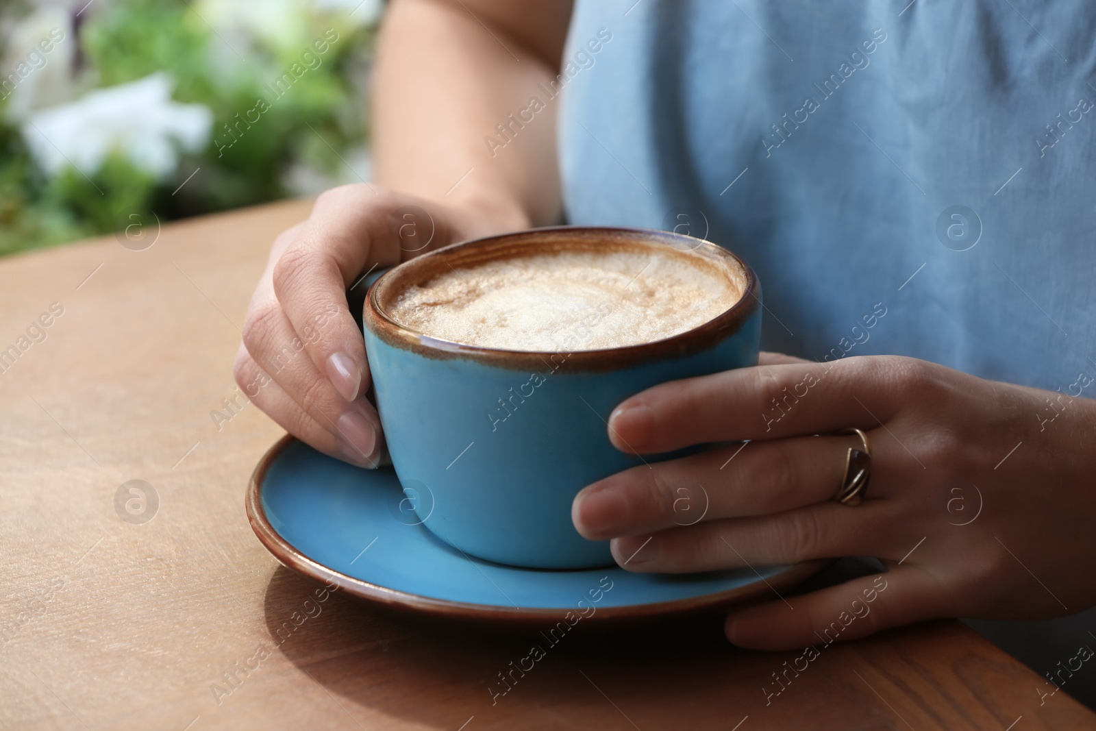 Photo of Woman with cup of fresh aromatic coffee at table, closeup