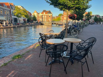 Leiden, Netherlands - August 1, 2022: Picturesque view of city street with cafe and beautiful buildings along canal