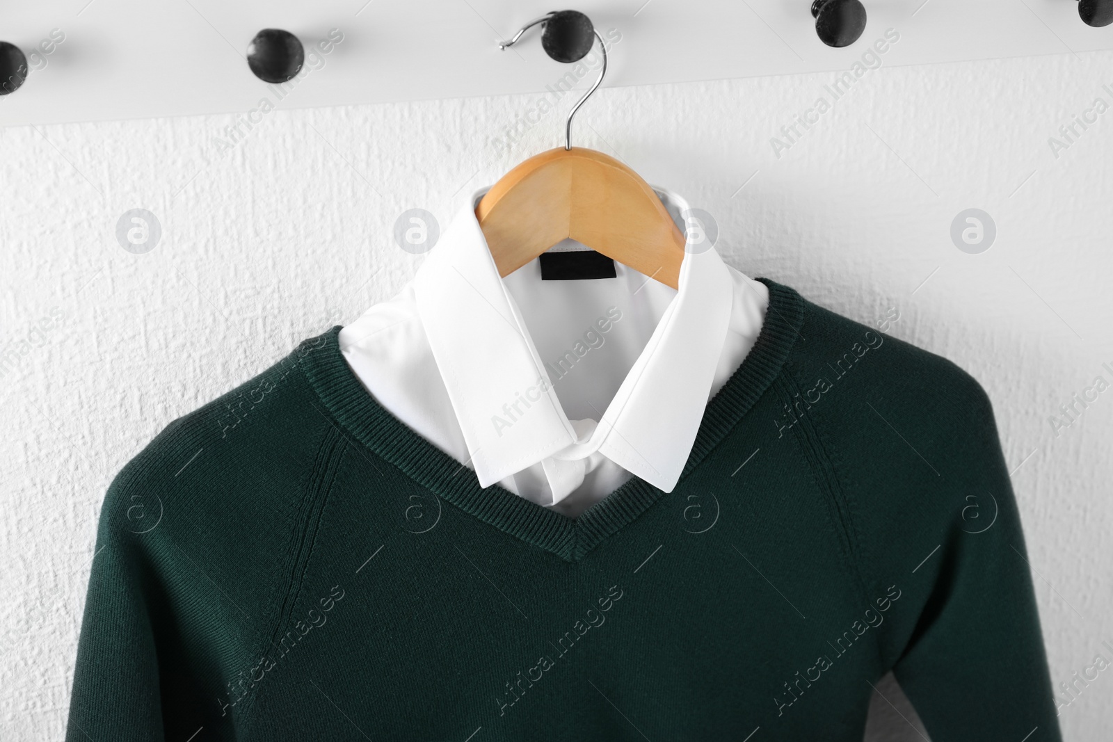 Photo of Shirt and jumper on hanger indoors. School uniform