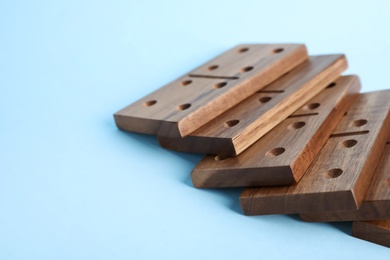 Photo of Fallen wooden domino tiles on light blue background