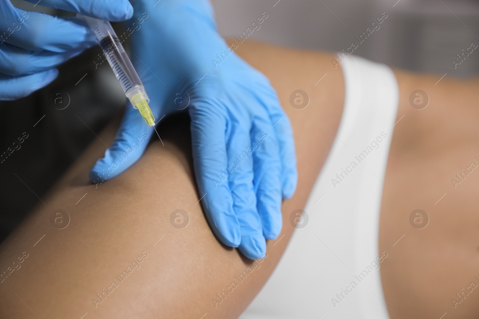 Photo of Young woman getting legs injection in salon, closeup