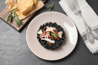 Delicious black risotto with seafood and cheese served on grey table, flat lay
