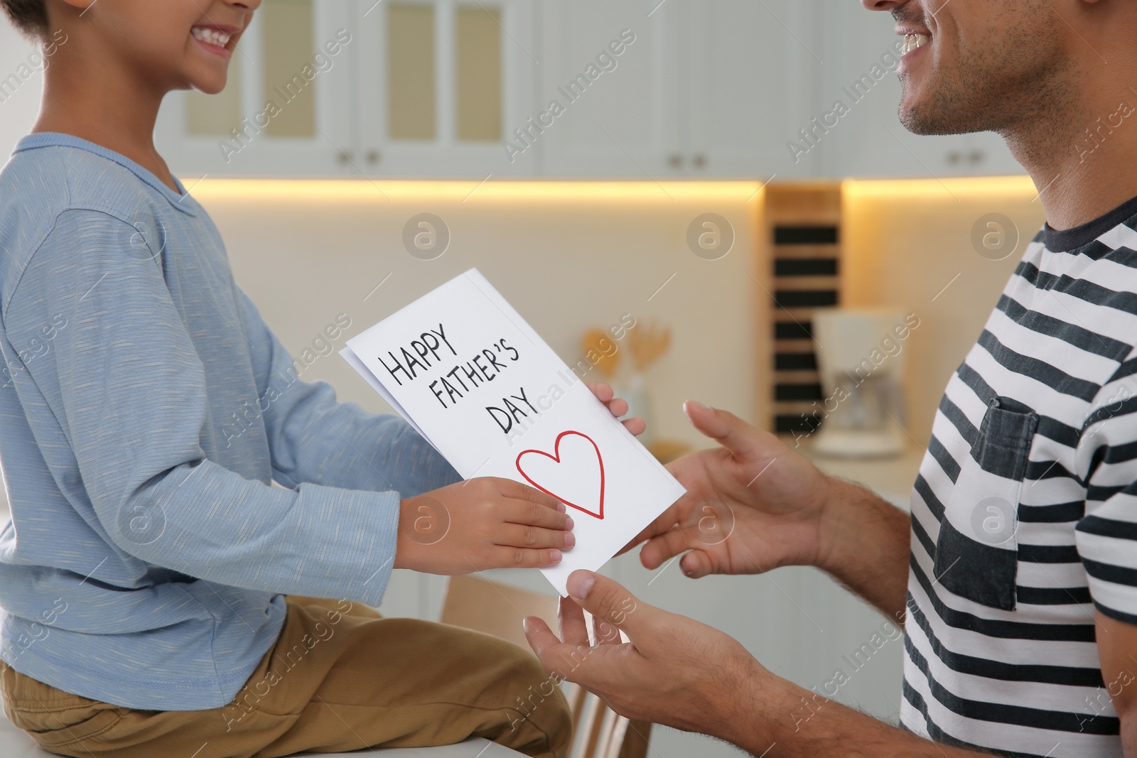 Photo of Little boy greeting his dad with Father's Day in kitchen, closeup