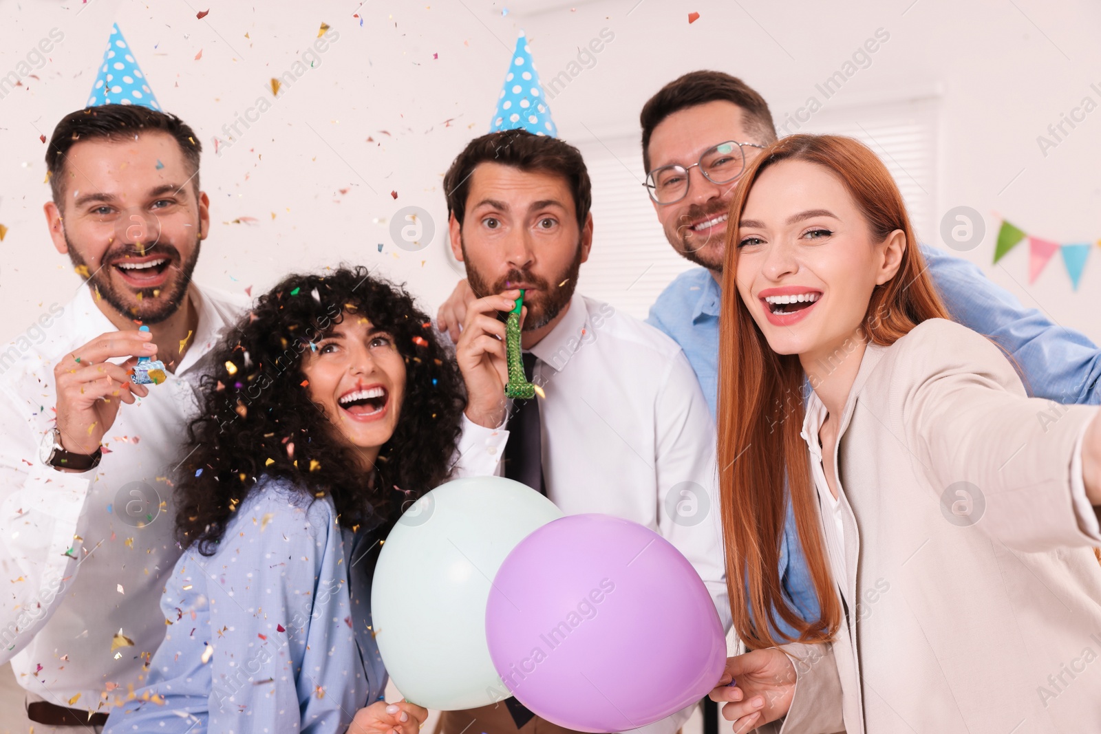 Photo of Coworkers taking selfie during office party indoors