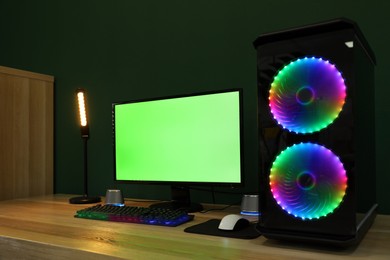 Photo of Modern computer and RGB keyboard on wooden table indoors. Mockup green screen