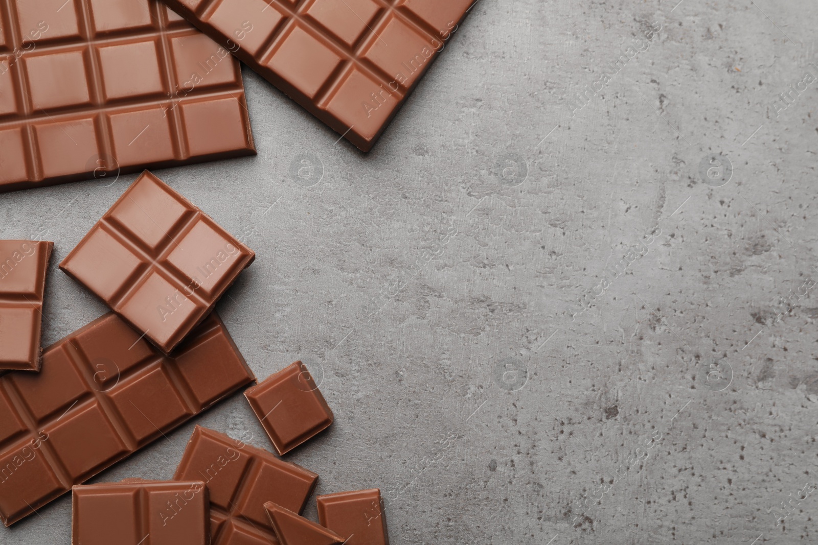 Photo of Delicious milk chocolate on grey table, flat lay. Space for text