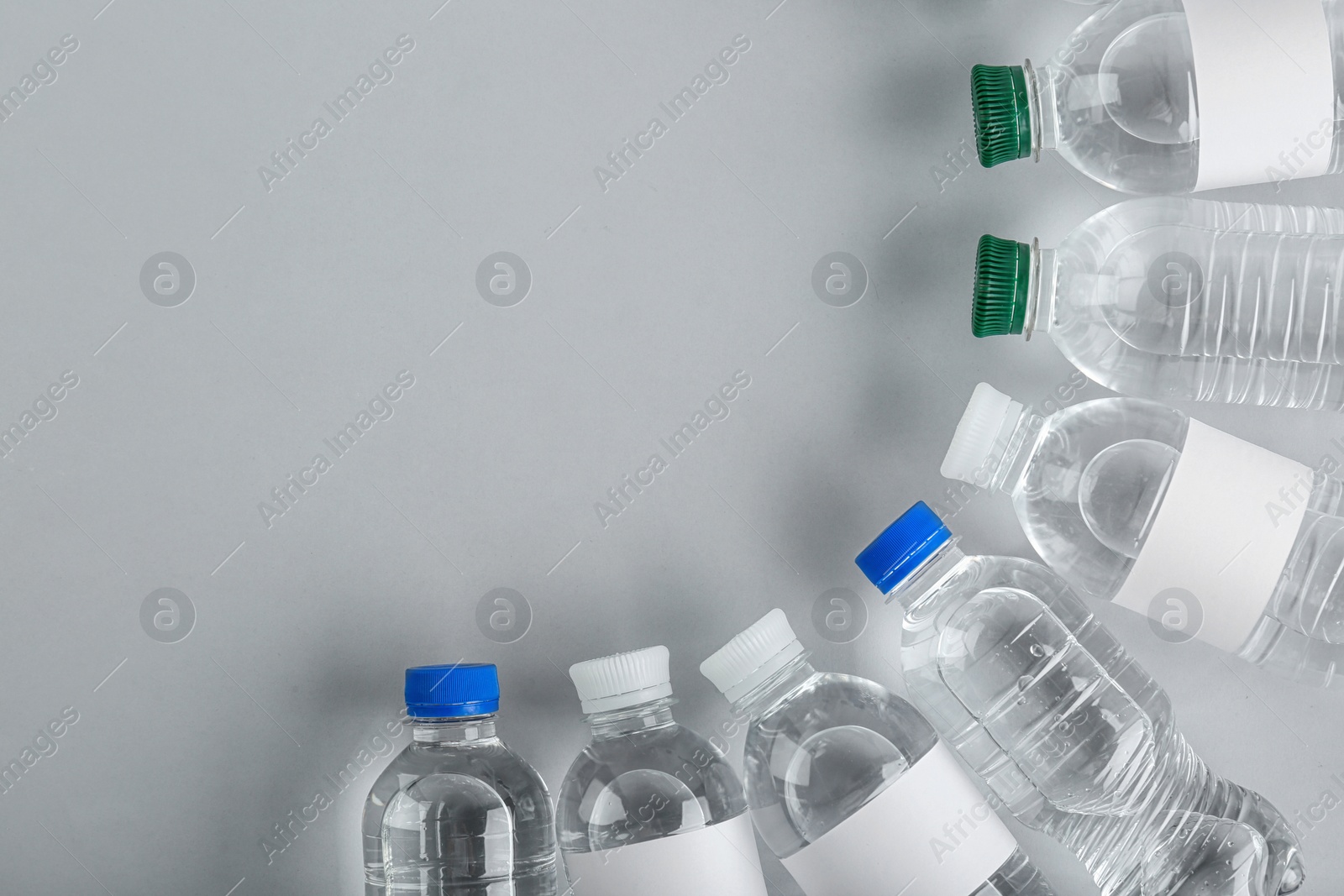 Photo of Bottles of water on light background, top view. Space for text