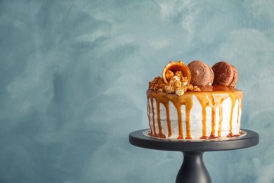 Dessert stand with delicious caramel cake on color background