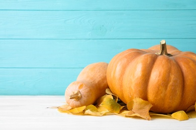 Photo of Ripe pumpkins on table against blue wooden background, space for text. Holiday decoration