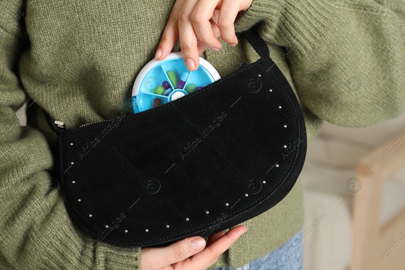 Photo of Woman putting pill box into bag indoors, closeup