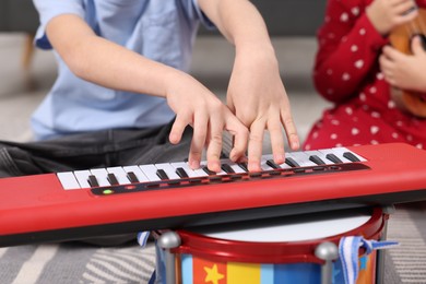 Photo of Little children playing toy musical instruments at home, closeup