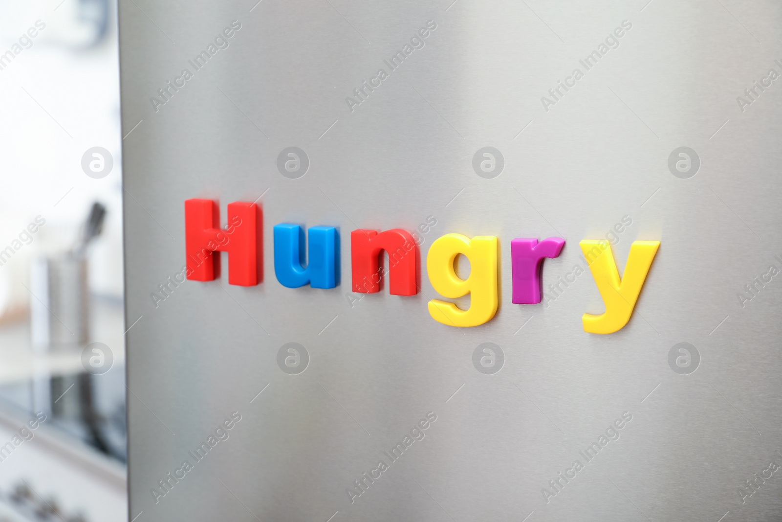 Photo of Word HUNGRY of magnetic letters on refrigerator door indoors