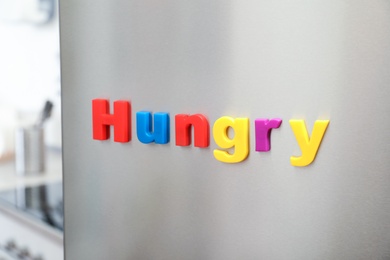 Photo of Word HUNGRY of magnetic letters on refrigerator door indoors