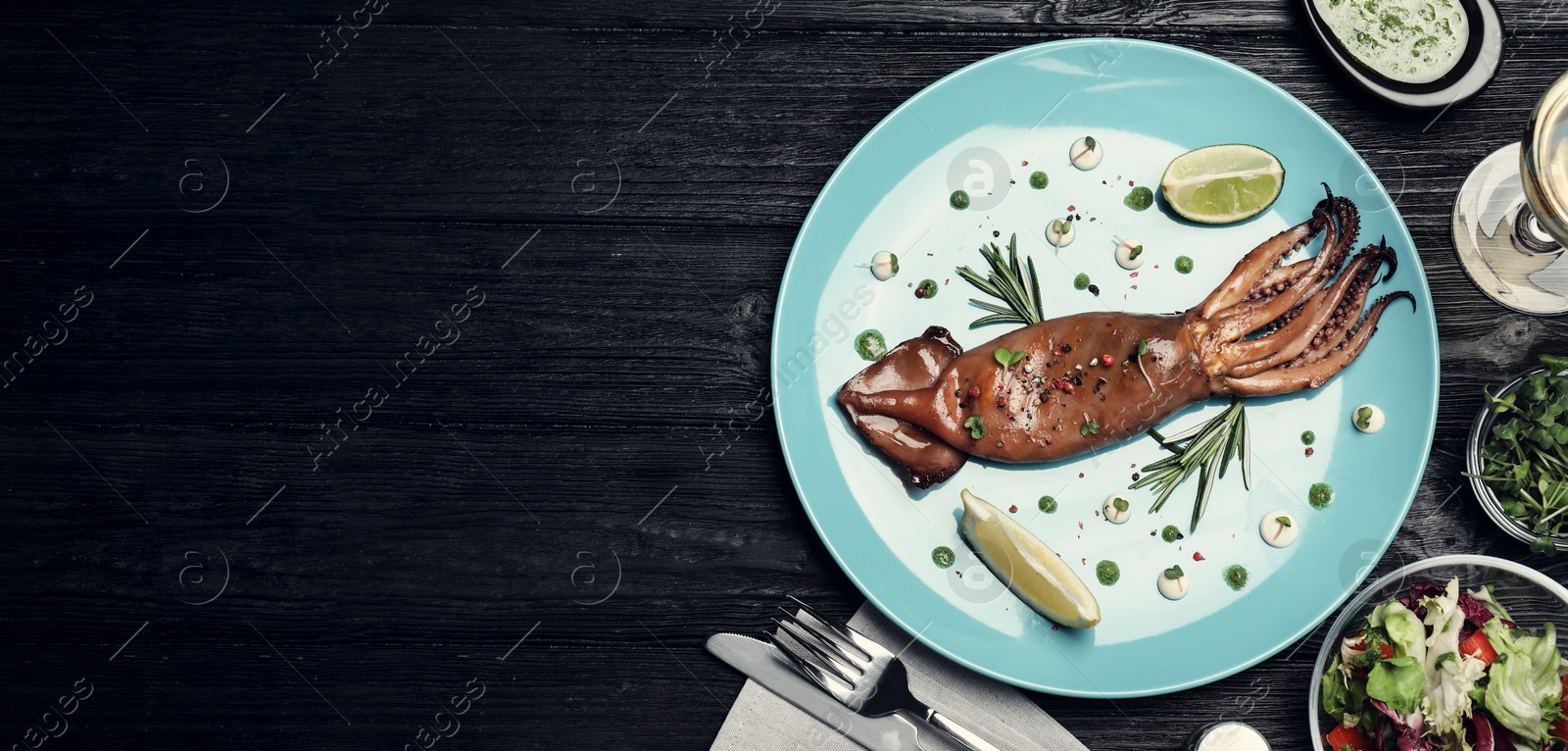 Image of Tasty grilled squid served on black wooden table, flat lay. Banner design with space for text